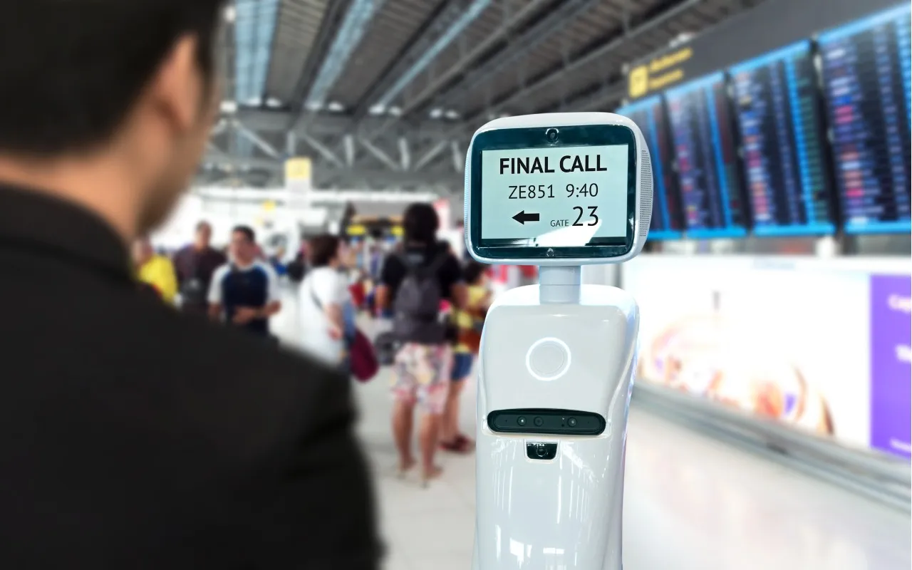 Një robot asistent duke ndihmuar një udhëtar në një aeroport modern, duke treguar teknologjinë AI në shërbimin turistik.