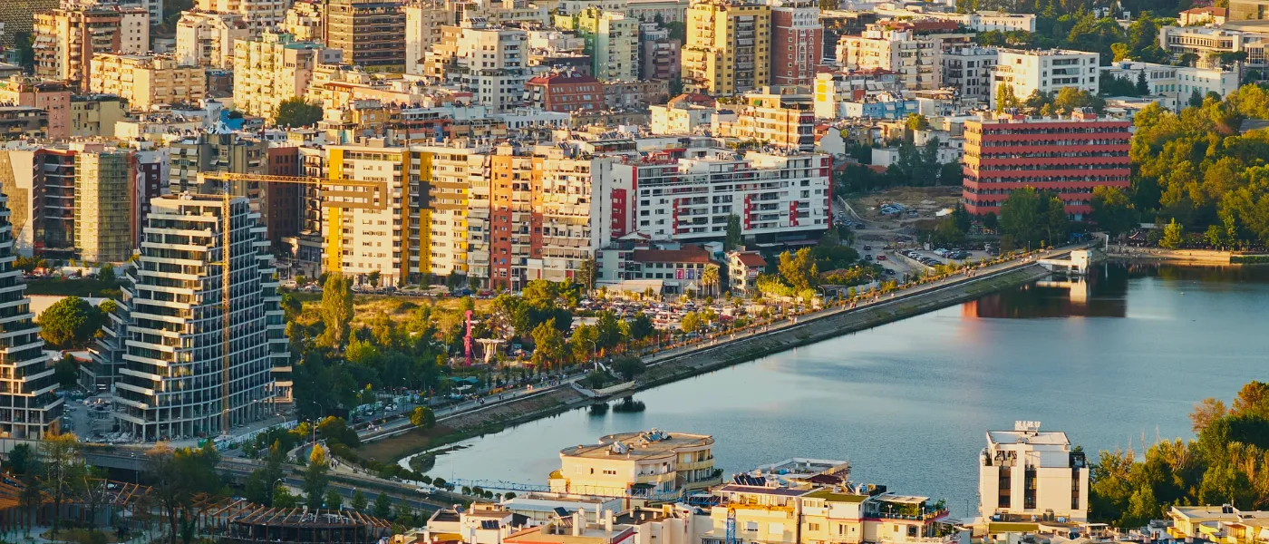 Pamje ajrore e një qyteti modern shqiptar me ndërtesa të reja dhe liqen, duke treguar zhvillimin urban dhe investimet në infrastrukturë.