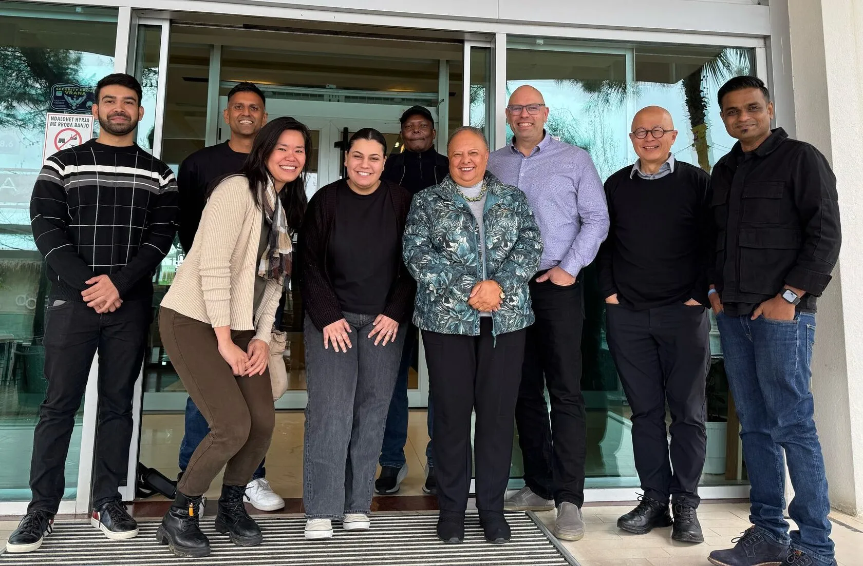 Një grup i larmishëm profesionistësh të qeshur, duke përfaqësuar komunitetin në rritje të nomadëve dixhitalë dhe lidhjet globale.