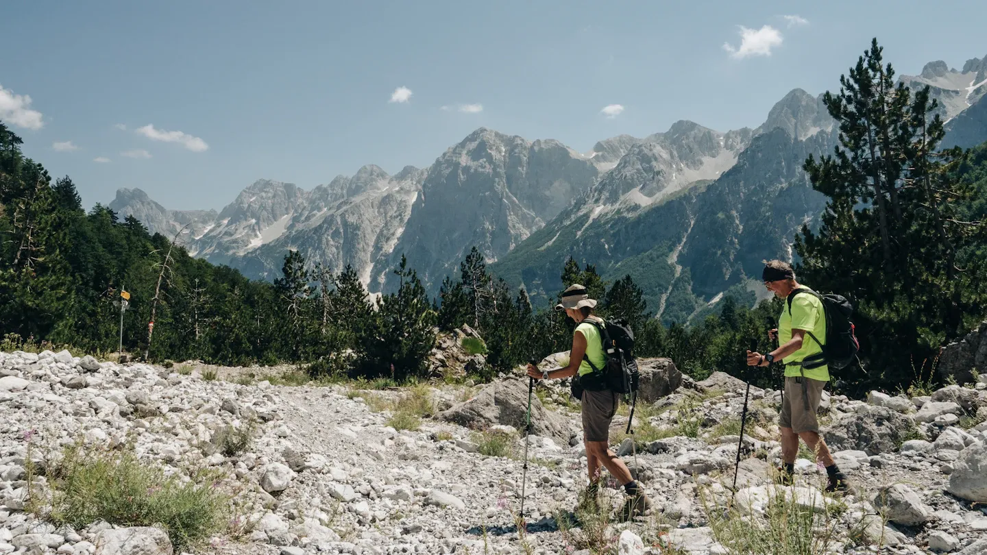Dy persona duke bërë shëtitje në natyrën malore të Shqipërisë, duke theksuar rëndësinë e aktivitetit fizik.